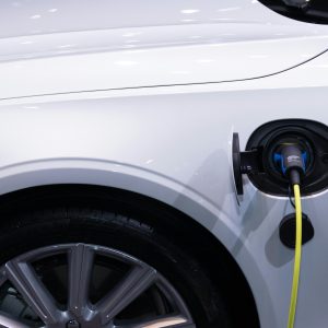 A white electric car is plugged in for charging, close-up view of the charging port.